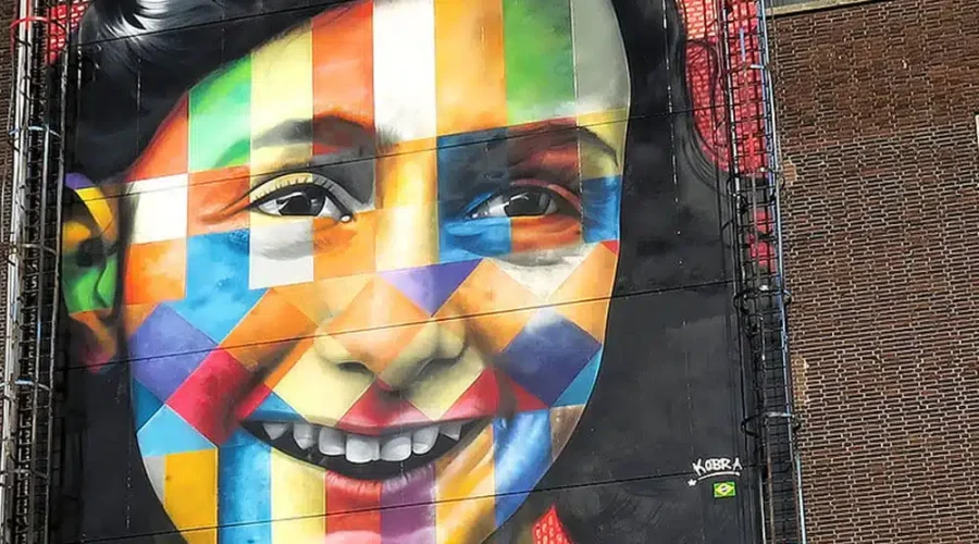 Colorful geometric mural of a smiling girl’s face on a brick building. Colorful geometric mural of a smiling girl's face on a brick building.