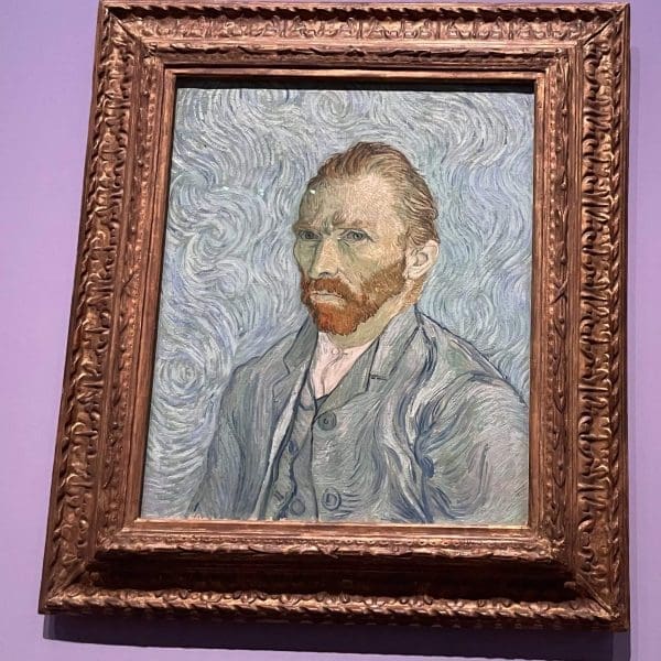 A framed painting of a man with reddish-brown hair and beard, wearing a blue coat, against a swirling blue background.
