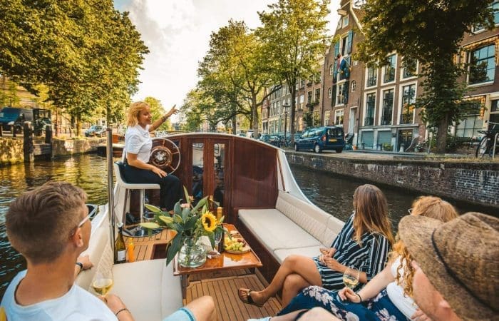 Private boat gliding through Amsterdam canal past historic merchant houses
