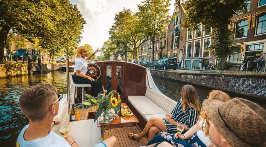 Private boat gliding through Amsterdam canal past historic merchant houses