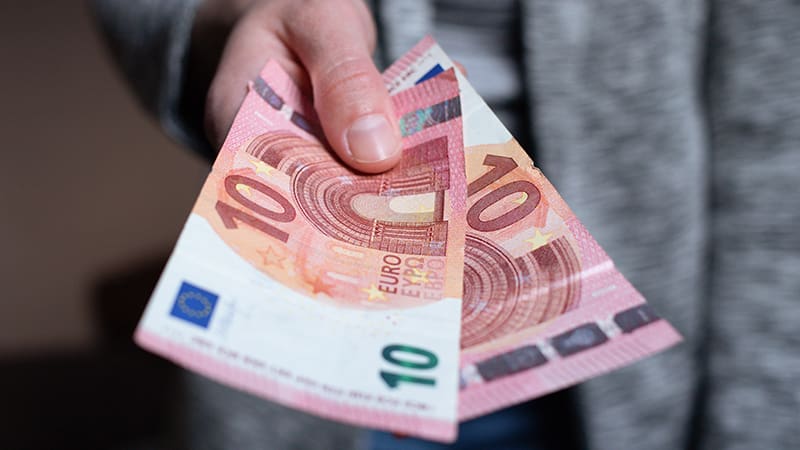 A hand holding euro banknotes, a common sight when tipping in Amsterdam and the Netherlands