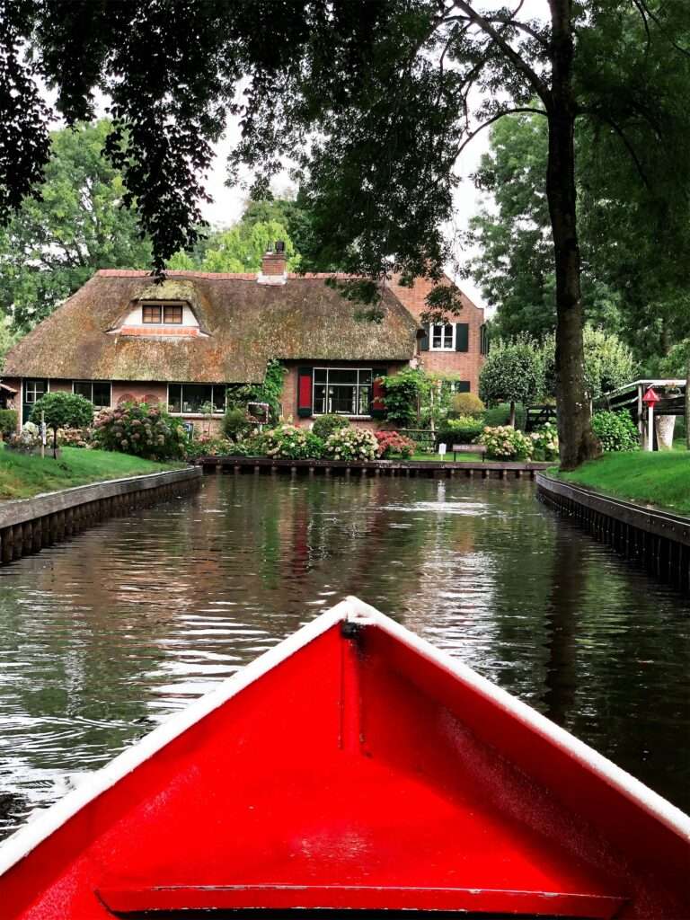 A boat on a canal in Giethoorn passing a cottage