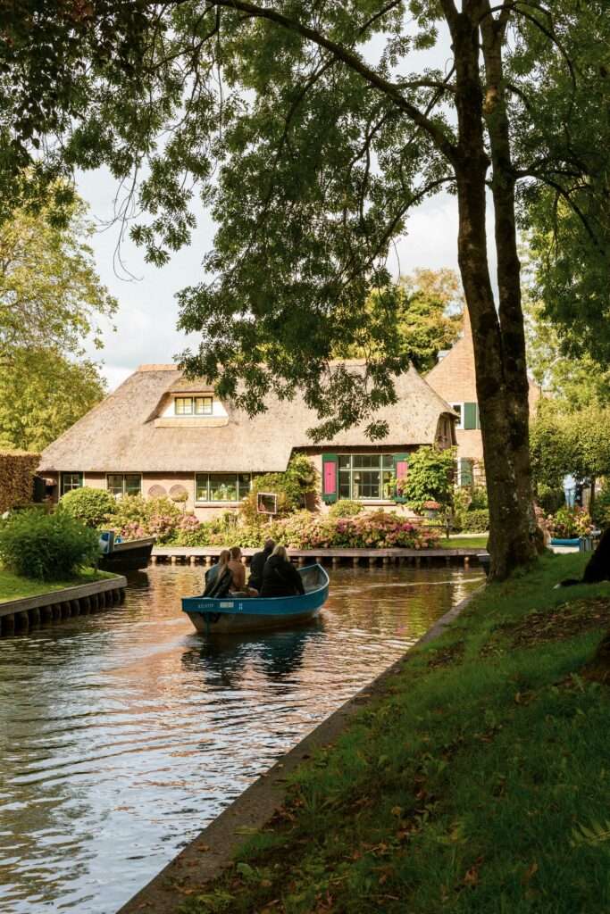 Guests on a private boat trip passing a canal-side house in Giethoorn