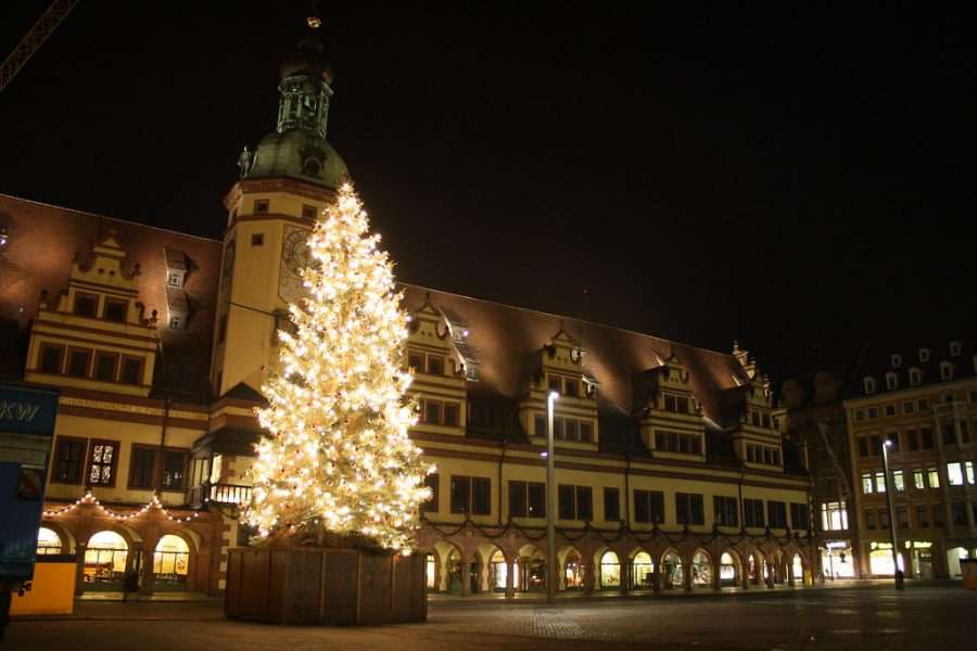 A Christmas tree lit in front of a town hall at night