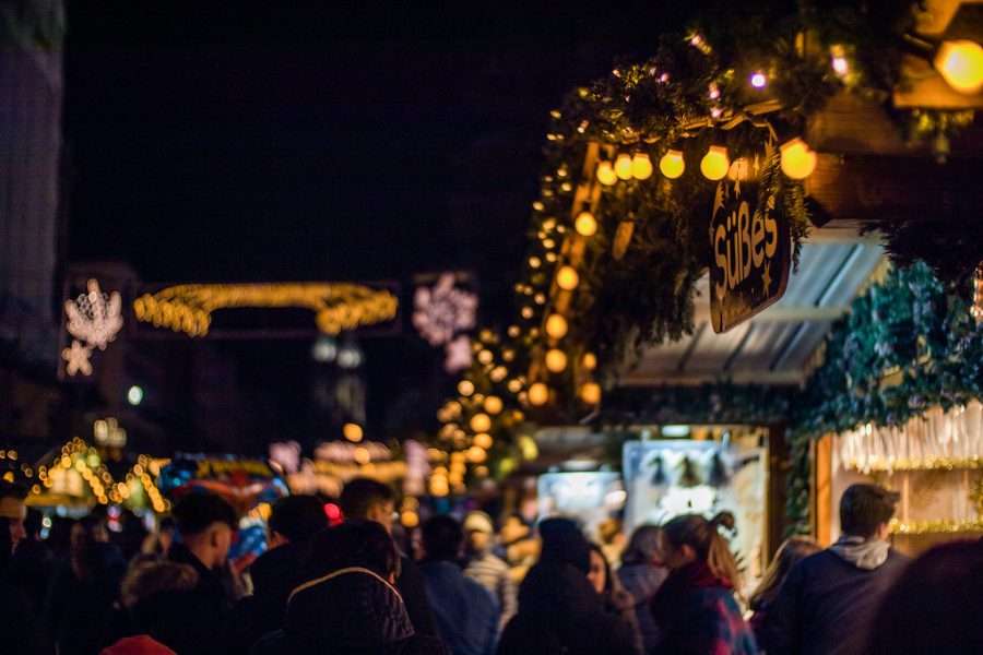 A Christmas market lane busy with people under strings of lights