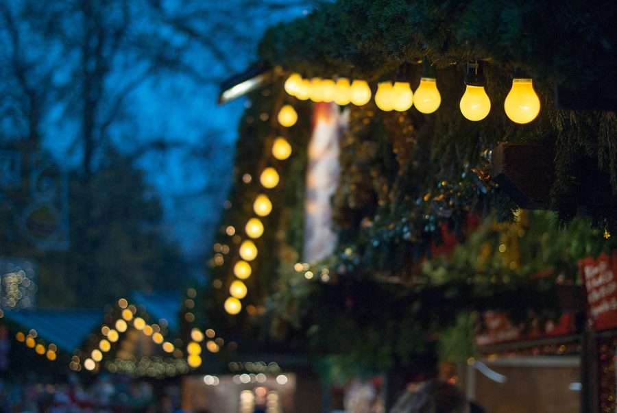 Stall roofs strung with lights at a Christmas market at dusk