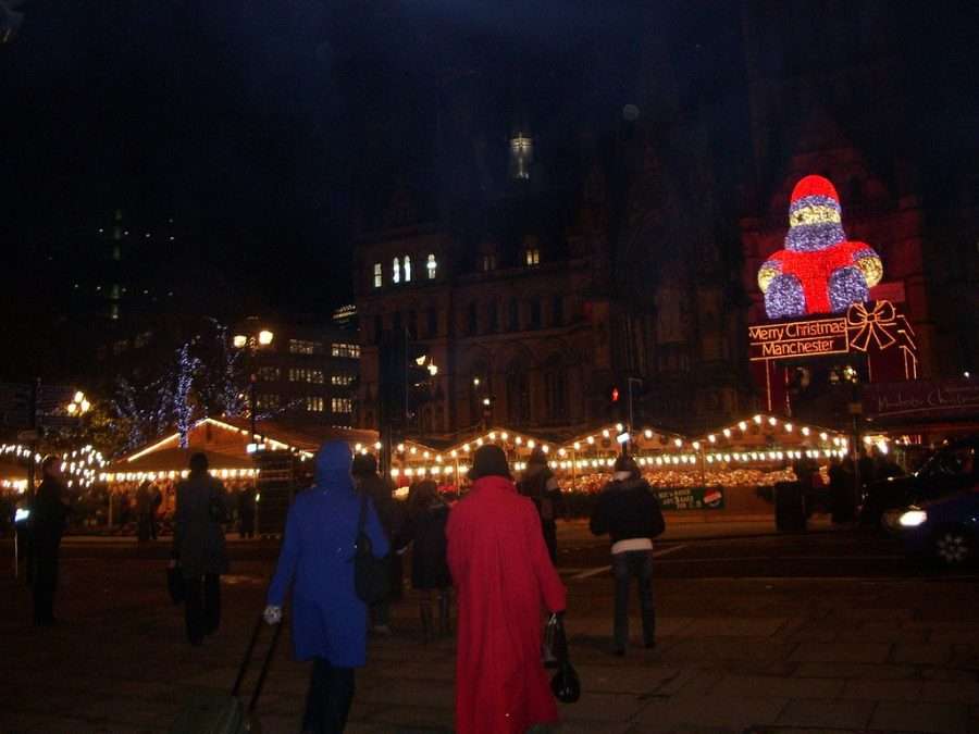 A Christmas market square under lights in the evening