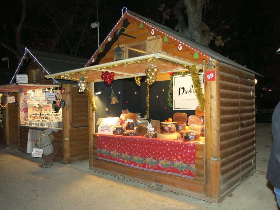 A wooden Christmas market chalet lit up at dusk